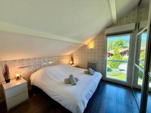 a bedroom with a white bed with two pillows on it at Le Jardin de Rose et Capucine, piscine et jardin avec terrasse in Gérardmer +29 photos