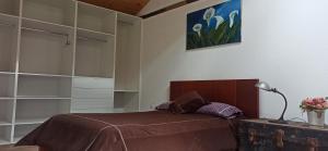a bedroom with a bed and a lamp and shelves at Confortable cabaña campestre in Ibarra
