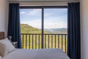 a bedroom with a bed and a large window at BABhouse Casa do Avô Pedoucas - Coração do Douro in Nagoselo do Douro