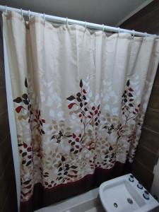 a bathroom with a shower curtain with flowers on it at Complejo belgrano in General Roca +4 photos