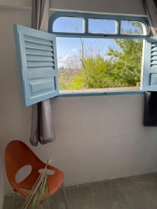 a chair and a window in a room at Suíte Aconchego in Areia
