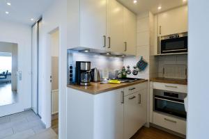 een keuken met witte kasten en een aanrechtblad bij Strandhochhaus SF11 in Cuxhaven