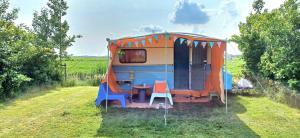 una roulotte con tavolo e sedie in un campo di Retro caravan de Duif vlakbij het Sneekermeer a Terzool