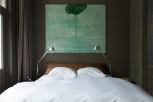 een bed met twee witte kussens en een schilderij erboven bij Blue Inspired by Manna in Nijmegen