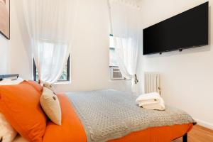 una camera con letto arancione e TV a schermo piatto di Aura Style 3BD Suite at Times Square Manhattan a New York