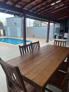 a wooden table with four chairs and a pool at Casa de Lazer com piscina in Pirassununga