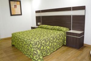 a bedroom with a bed with a green bedspread at Hotel Castillo in Mexico City