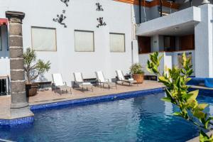 a swimming pool with chairs and a building at Hotel Santiago De Compostela - Guadalajara Centro Historico in Guadalajara