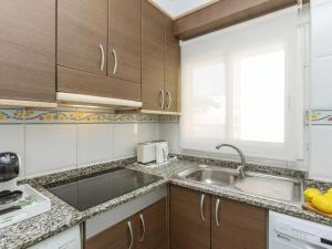 a kitchen with wooden cabinets and a sink at Apartment Oasis Cambrils by Interhome in Cambrils