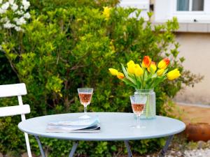 a table with two glasses and a vase of flowers at Holiday Home L'Horizon by Interhome in La Bernerie-en-Retz