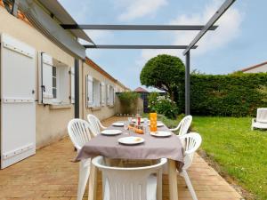 a table with white chairs on a patio at Holiday Home L'Horizon by Interhome in La Bernerie-en-Retz