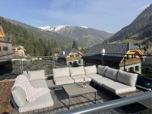 eine Couch und zwei Stühle auf einem Balkon mit Bergen in der Unterkunft Haus Ganbei in Donnersbachwald
