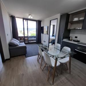 eine Küche und ein Wohnzimmer mit einem Glastisch und Stühlen in der Unterkunft Departamento moderno tipo mariposa, cerca del centro in Temuco