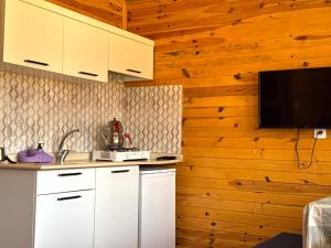 a kitchen with white cabinets and a flat screen tv at Venüs Gold Bungalov Adrasan in Kumluca