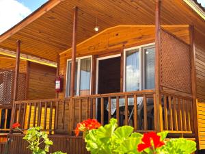a wooden house with a porch with flowers in front at Venüs Gold Bungalov Adrasan in Kumluca