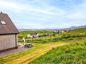 a picnic table in a field next to a house at Holiday Home Quiraing Cottage by Interhome in Flodigarry