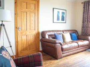 a brown leather couch sitting in a living room at Holiday Home Quiraing Cottage by Interhome in Flodigarry +22 photos