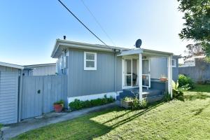 a small house with a fence in a yard at Bluebell Cottage on Matakana Coast Pet Friendly! in Snells Beach