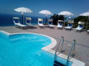 a swimming pool with chairs and tables and umbrellas at Agriturismo La Palombara in Paola