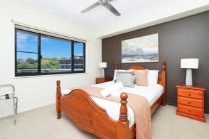 ダーウィンにあるSuperb Waterfront Lagoon Views & Balcony Relaxingのベッドルーム1室(大型木製ベッド1台、窓2つ付)