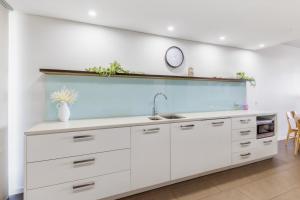 a kitchen with white cabinets and a sink at Delightful Waterfront Lagoon Views & Restaurants in Darwin +7 photos