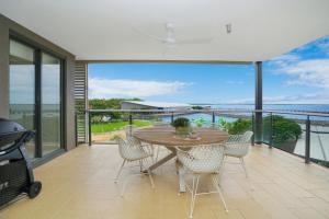 ダーウィンにあるTranquil Waterfront Lagoon Views BBQ & Cafesのバルコニーにテーブルと椅子が置かれたダイニングルーム