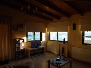 a living room with a tv and a couch and windows at Gramvoussa Bay in Kissamos