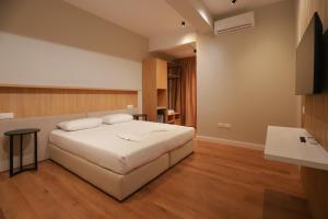 a bedroom with a large white bed and wooden floors at Hotel Relax City Center in Tirana