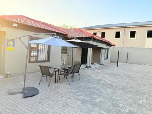 a patio with a table and chairs and an umbrella at Whizzy lifestyle lodge in Duvhapark