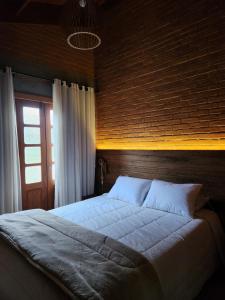 a bedroom with a large bed with a brick wall at Chalé Sol - Vila Doiideira - lindo aconchegante e no centro de Ibitipoca in Lima Duarte +20 photos