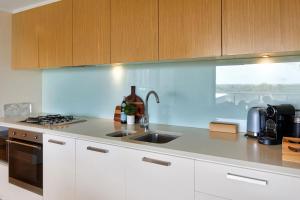 a kitchen with white cabinets and a sink at Charming Waterfront Lagoon Views & Restaurants in Darwin +4 photos