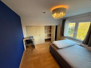 a bedroom with a bed and a desk and a chandelier at The Beautiful White Villa in Kortenberg