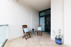 a patio with two chairs and a table on a porch at Ideal CBD Location with Harbour Views Pool Gym & BBQ in Darwin