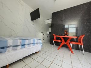 ein Schlafzimmer mit einem Bett, einem Tisch und einem Fernseher in der Unterkunft No coração da Praia do Frances in Marechal Deodoro