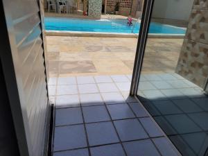 Blick auf den Pool durch eine Glastür in der Unterkunft No coração da Praia do Frances in Marechal Deodoro