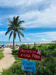 eine Palme und ein Schild am Strand in der Unterkunft No coração da Praia do Frances in Marechal Deodoro