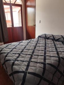 a bed with a black and white comforter in a bedroom at Nuevo departamento en el centro de Coatepec in Coatepec