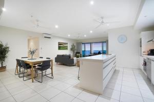Una cocina y una sala de estar con mesa y sillas. en Sub-Penthouse Stunner Harbour Views & Pool, en Darwin