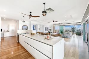 cocina y sala de estar con armarios blancos y una gran isla en Ultimate Penthouse Majestic Harbour Views & Pool, en Darwin