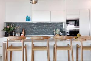 una cocina con armarios blancos y 4 taburetes en Ultimate Penthouse Majestic Harbour Views & Pool, en Darwin