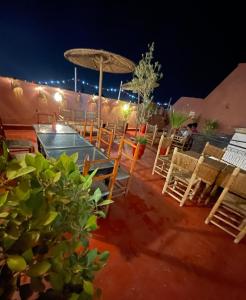 eine Gruppe Stühle, ein Tisch und ein Regenschirm in der Unterkunft Riad dar Assou in Marrakesch