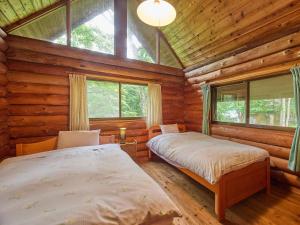 ein Schlafzimmer mit zwei Betten in einer Blockhütte in der Unterkunft ルネス軽井沢-高原の貸切コテージでBBQ and 焚火を満喫- in Tsumagoi