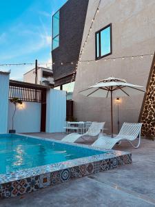 una piscina con due sedie e un ombrellone di 墾丁恆春包棟 l 洛夫特Looft民宿 a Città Vecchia di Hengchun