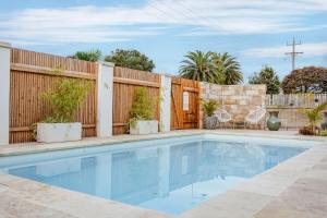 a swimming pool in front of a wooden fence at Bellvilla - Bluebonnet Suite in Merimbula