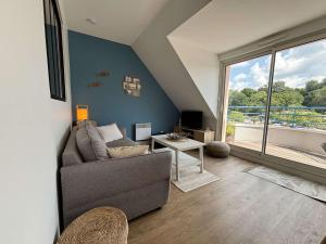 a living room with a couch and a large window at Appartement cosy pour 4 personnes au cœur de la Forêt-Fouesnant - FR-1-481-179 in La Forêt-Fouesnant