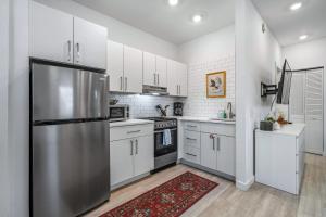 a kitchen with white cabinets and a stainless steel refrigerator at Courtyard Cottage- 15 Min Walk to Downtown in Saint Augustine +20 photos