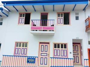 a white building with colorful doors and a balcony at Natura 2 habitaciones 2 baños Rosado in Salento