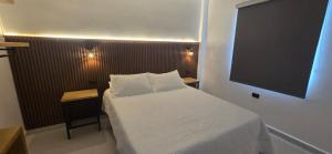 a bedroom with a white bed and a large screen at Natura 2 habitaciones 2 baños Rosado in Salento