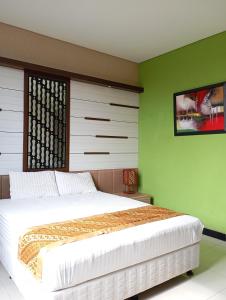 a bedroom with a large bed and green walls at Graha Laweyan Solo in Bonorejo +2 photos