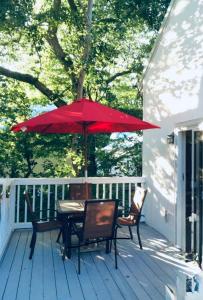 a table and chairs with a red umbrella on a porch at Perfect Family Vacation at Bethany Beach Cottages! in Bethany Beach